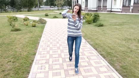 Beautiful-brunette-woman-is-reading-something-on-mobile-phone-walking-near-the-home.