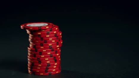 A-stack-of-red-poker-chips-slides-in-on-a-black-background.-At-the-end-the-hand-takes-them-away.