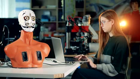 Human-like-robot-is-moving-its-mouth-under-control-of-a-young-woman