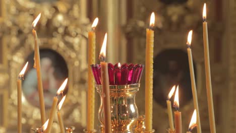 Las-velas-se-queman-en-una-catedral-cristiana,-nadie,-el-oro-está-en-todas-partes,-fuego,-iconos,-vídeo-4k