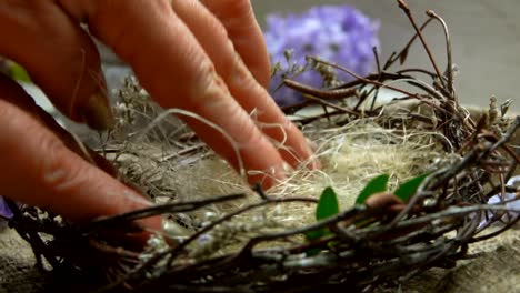 La-mano-femenina-pone-el-sisal-y-las-ramitas-verdes-en-el-nido-de-Pascua.