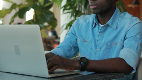 Afrikanischer-amerikanischer-Mann,-der-Laptop-Computer-im-Café-benutzt,-um-Geschäftsideen-zu-teilen