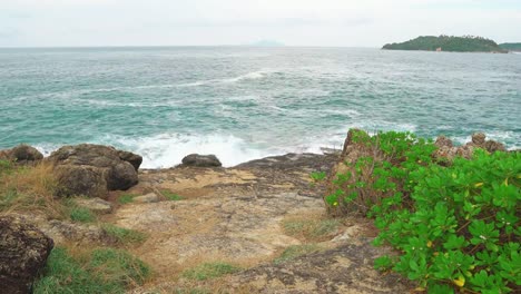 tropical-island-in-the-distance-from-the-shore-through-the-Strait.-sea-waves-break-on-the-shore,-rest-and-travel