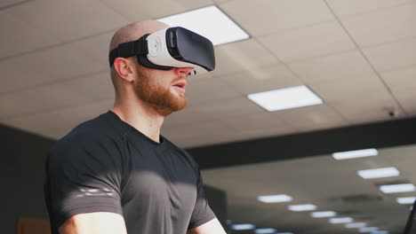 Young-strong-man-exercising-on-treadmill-at-the-gym,-wearing-VR-glasses,-slow-motion,-close-up