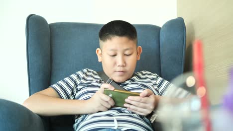 Young-teenager-playing-game-on-smartphone-in-cafe