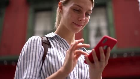 Sonriente-mujer-hipster-disfrutando-de-tiempo-para-actualizar-el-perfil-social-en-el-sitio-web-para-conocer-a-nuevas-personas-virtuales-utilizando-la-conexión-pública-a-Internet-durante-las-visitas-turísticas-en-vacaciones