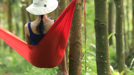 Mujer-relajándose-en-hamaca-con-teléfono-inteligente-en-la-selva-tropical,4k