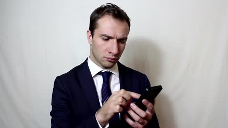 Young-handsome-businessman-pulls-out-his-smartphone-from-his-pocket-and-looks-through-the-news-feed.