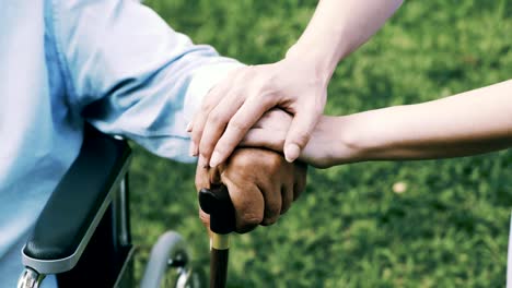 Nurse-comforting-senior-man-sitting-in-wheelchair.