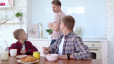 Feliz-familia-gay-dos-padres-e-hijo-están-desayunando-en-la-cocina.