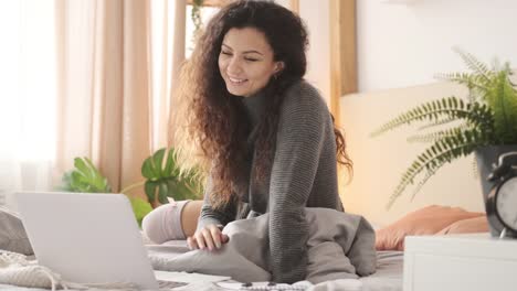 Mujer-video-chatconeando-usando-computadora-portátil-en-la-cama