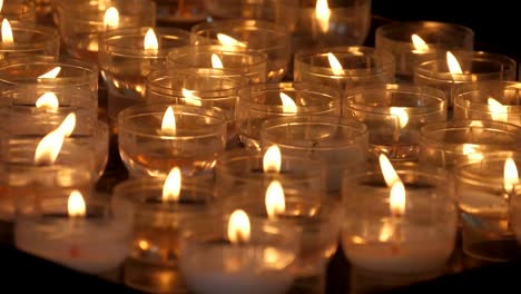 Schöne-Aussicht-auf-viele-Kerzen-im-Freien,-die-in-einer-katholischen-christlichen-Kirche-in-Belgien-in-Zeitlupe-angezündet-wurden.-Sie-sehen-inspirierend-und-feierlich-aus.