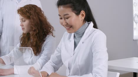 Multiethnic-Students-in-Lab-Coats-Using-AR-Touchscreen-Devices-in-Class