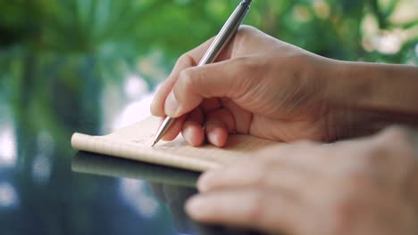 4K-Video-Kopie-Raum-des-Mannes-Hand-schreiben-in-weißen-Notizbuch-mit-Bokeh-Licht-im-Café-Hintergrund.