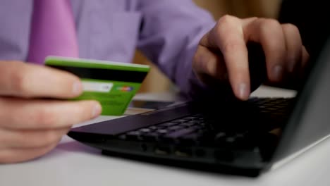 Un-hombre-de-negocios-con-camisa-y-corbata-morada-está-haciendo-un-pago-a-la-banca-por-Internet.-Compras-en-línea-con-tarjeta-de-crédito-en-el-ordenador-portátil.