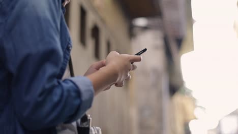 Close-up-hands-young-asian-traveler-using-smart-phone-sharing-social-media,-online-shopping-at-a-small-street-in-Bangkok-Thailand.-Enjoying-traveling-on-holiday-summer.-Solo-travel-concept.