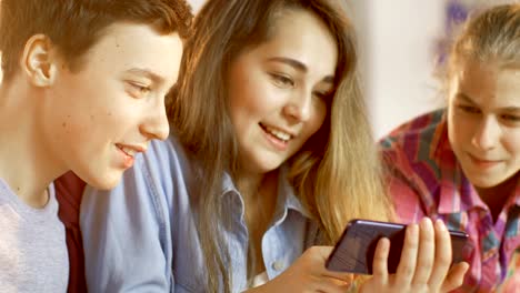 Boy-and-Two-Girls-Working-on-a-Schools-Science-Class-Project-Watch-Popular-Videos-on-Smartphone.