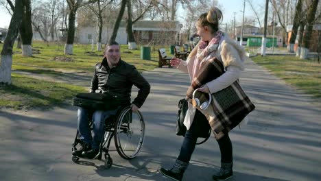 Disabeld-man-in-wheelchair-and-girl-walk-along-embankment-smiling,-laughing,-and-talking