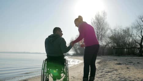 Disabled-man-in-wheelchair-and-girl-raise-their-hands-to-the-sky