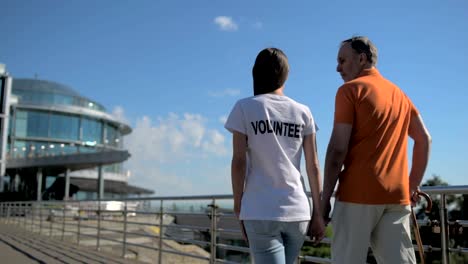 Helpful-female-volunteer-walking-with-a-senior-man