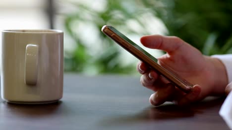 Close-Up-of-Woman's-Hands-Using-Mobile-Phone-at-Coffee-Break