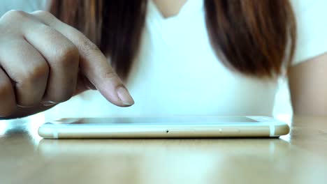 Close-up-of-young-woman-hands-using-smartphone-on-the-table.