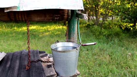 Gut-mit-Wasser-ist-Eisen-Eimer-daneben.-Gewinnung-von-Wasser-in-den-ländlichen-Gebieten.-Leben-ohne-fließendes-Wasser