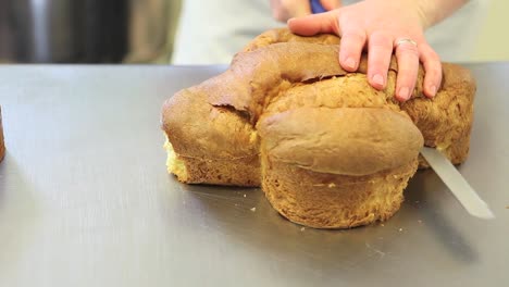 Pastry-Chef-Hände-schneiden-Biskuit-süßen-Brot-Ostern-Taube-Nahaufnahme-auf-der-Arbeitsplatte-in-der-Konditorei