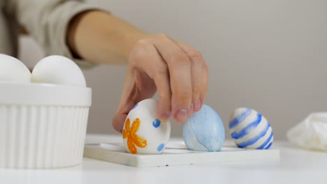 Unrecognizable-woman-puts-an-ornate-Easter-egg-on-a-stand.-Preparing-for-the-holidays.