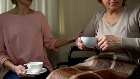 Hija-tratando-de-convencer-a-mamá-para-ir-al-hogar-de-ancianos,-sentados-sobre-la-taza-de-té