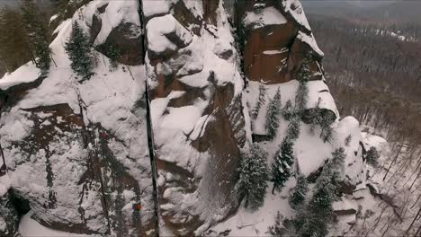 Aerial-view-of-a-rock-climber-climbing-a-steep-cliffs-during-a-sunny-winter-day.