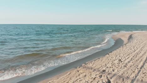 Drone-bewegt-sich-hinter-Frau-in-Sport-Wear-hält-Yoga-Asana-Position-am-Meer-oder-Ozean-Sandstrand.-Windige-sonniges-Wetter.-Luftaufnahme-des-friedlichen-Gesundheit-Mädchen-Praxis-durchführen