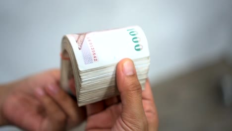 Cerrar-las-manos-contando-de-thousansds-dinero-de-baht-tailandés