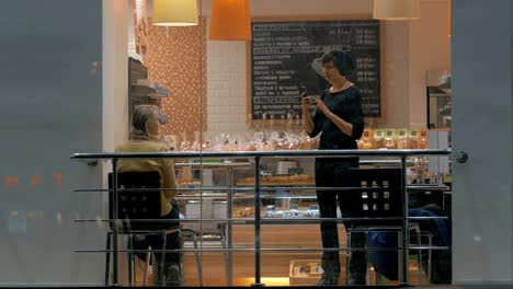 Woman-with-cell-making-photos-of-friend-during-the-meeting-in-cafe