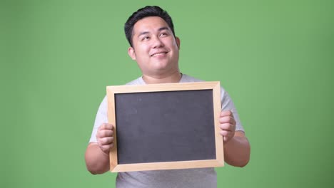 Young-handsome-overweight-Asian-man-against-green-background