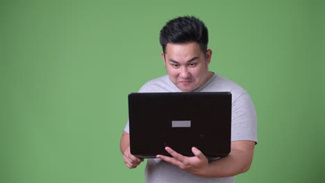 Young-handsome-overweight-Asian-man-against-green-background