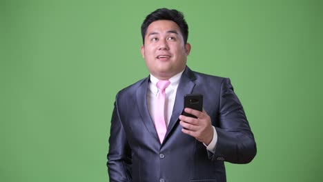 Young-handsome-overweight-Asian-businessman-against-green-background