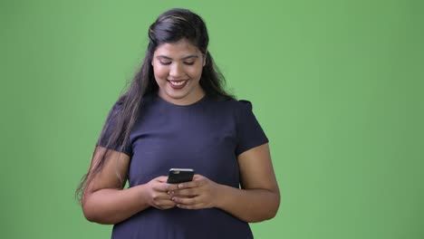 Young-overweight-beautiful-Indian-businesswoman-against-green-background