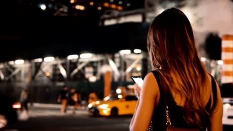 Mujer-hermosa-joven-parado-en-el-tráfico-de-gente-en-Nueva-York,-Estados-Unidos-en-la-noche-y-el-uso-de-smartphone