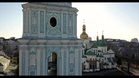 A-bird's-eye-view,-panoramic-video-from-the-drone-in-FullHD-to-the-Saint-Sophia's-Cathedral-the-bell-tower-and-main-building-in-the-city-of-Kiev,-Ukraine-against-a-bright-sun.