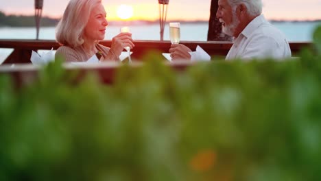 Kaukasische-Senioren-mit-Abendessen-bei-Sonnenuntergang-am-Strandhotel