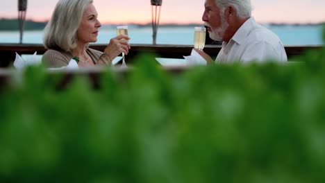 Caucasian-seniors-dining-at-sunset-at-beachfront-hotel