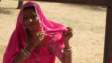 Rajasthani-woman-adjusting-her-pink-sari-and-getting-ready-in-front-of-a-mirror-outdoor