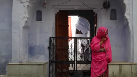 Schöne-Frau-in-Rosa-Saree-warten-auf-ihren-Mann-auf-einer-Straße-in-Pushkar,-Rajasthan,-Indien