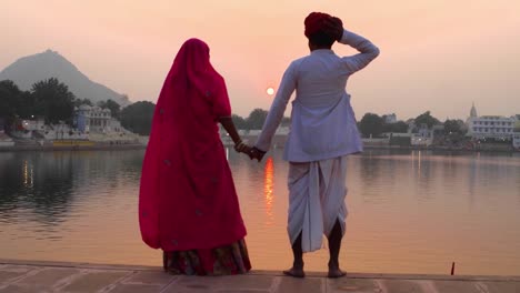 Pareja-romántica-indio-en-traje-tradicional-que-observa-el-sol-ir-abajo-en-el-lago-de-Pushkar