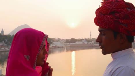 Marido-y-mujer-hablando-contra-la-hermosa-puesta-de-sol-en-el-lago-de-Pushkar,-India,-mano