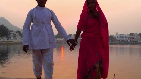 Couple-walk-towards-camera-and-beyond-against-the-setting-sun