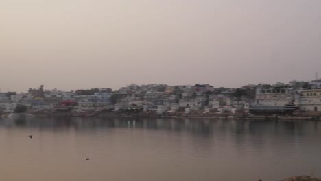 Pan-away-from-Indian-couple-in-traditional--dress-taking-photos-of-sunset-at-holy-Pushkar-lake,-Rajasthan