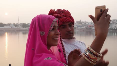 Handheld,-Rajasthani-couple-taking-selfies-from-a-mobile-phone-camera-at-the-Pushkar-Lake,-India