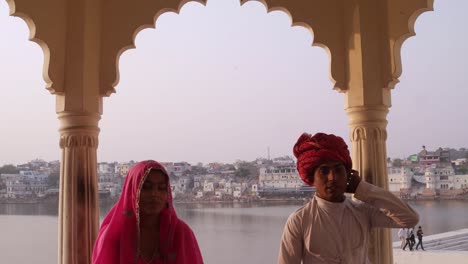 Kippen-Sie-auf-attraktive-indische-Paare-in-Tracht-mit-Pushkar-See-im-Hintergrund,-Rajasthan,-Indien